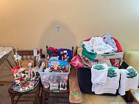 overall view of mixed lot showing ornaments tray, plastic bin of figures, box of linens and hand towels draped
