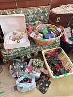 Overall lot showing wicker basket with tins, white wreath in box, laundry basket with ornaments, silver ornament cluster