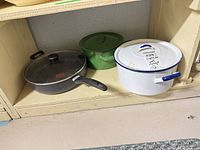 Overview of frying pan, green pot, white pot on shelf