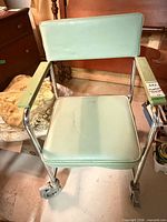 Front view of commode chair showing seat, backrest, casters