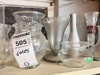 Shelf with clear ruffled vase, frosted pedestal vase, small clear pot, white ceramic bud vase and cut glass vase with ruby accent