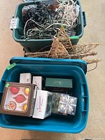 Two plastic storage tubs showing bundled light strings, boxed ornaments and wired gold star