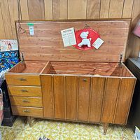 Front view showing drawers, legs, and hinged lid open