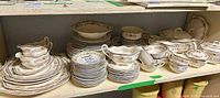 Full set displayed on shelving showing plates, bowls, gravy boats, serving pieces
