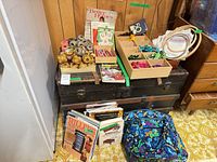 Overview of lot on trunk showing threads, wooden tray, books, hoops, backpack