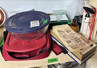 Shelf view of mixing bowl, insulated bag, mirrored stand, sauce jar and cookie press boxes