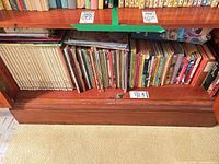 Shelf showing encyclopedia set left and stacks of children’s books right