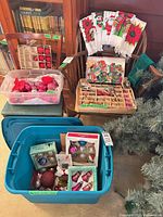 Overall lot showing towels draped on chair, ornament boxes in trays and storage tubs