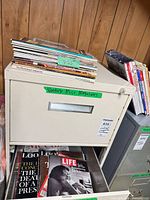 Stack of assorted magazines on top of metal cabinet