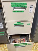 Filing cabinet with labeled drawers indicating magazine titles and lot sticker