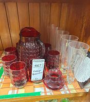 Pitcher, six tumblers, champagne flutes and paper doilies on shelf