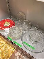 Shelf view showing two red snowman plates, several pressed glass bowls, star dish, Iittala Flora platter with bowl