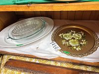 Shelf view showing oval white platter, two Pyrex glass bakers nested together, and round gold tole tray