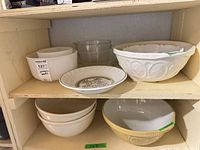 Shelf showing multiple ceramic and glass bowls plus recipe plate