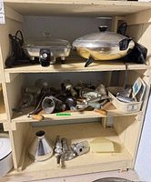 Shelf view with two electric skillets and multiple grinder parts