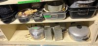 Shelf view showing kettle, graters, aluminum pot, springform pans, bundt pan, cords