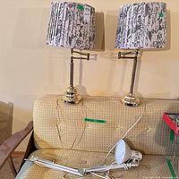 Overall view of two brass table lamps with shades and white desk lamp arm on couch