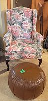 Floral wingback chair and brown vinyl ottoman viewed together