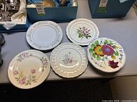 Five dinner plates laid out plus stack of additional floral dinner plates