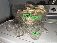 Pressed glass punch bowl padded with paper, plastic ladle, two handled cups visible