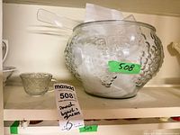 full view of pressed glass punch bowl, ladle inside, one punch cup beside