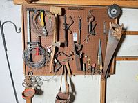 Pegboard view with hand saws, mallet, axe, clamps, screwdrivers, plane and wire coils