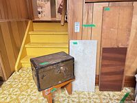 overview of lot showing metal trunk on stool, 2 wood boards and tile leaning against wall