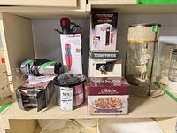 Group shot of all boxed and unboxed kitchen appliances plus lamp on shelf
