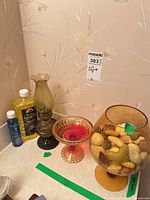 Overall lot showing oil lamp, pink compote, glass bowl with shells, lamp oil and cleaner