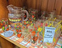Group shot of pitcher, decorated glasses and metal coasters