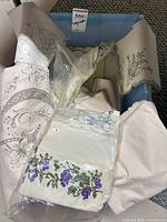 Bin containing assorted embroidered table linens