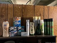 Shelf with Softsoap body wash, curlers boxes, Toni perm rods, Dove spray, Zest soap, Olay lotion, Pantene, Brut, Garnier Fructis