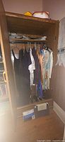 Wardrobe with hanging dresses, dance costumes, shoes and sheet boxes visible