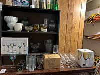 overview of shelving with glassware, boxed sets, milk glass, tumblers, shot glasses