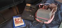 Polaroid Impulse camera, Kodak Colorburst 250 camera, Polaroid booklet, pink bag on surface
