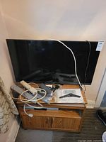 Sharp 40" LCD TV on stand with cables and remote visible