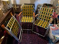 Three aluminum webbed lawn chairs folded and standing