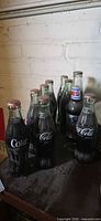 Group of nine vintage Coke and Pepsi bottles on shelf