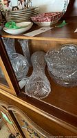 Shelf with multiple cut crystal vases and bowls