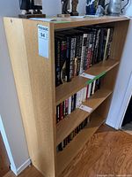 Left-front angle of light wood bookcase with books on three shelves