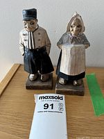 Front view of two signed Quebec wood carvings on bases, sea captain and wife