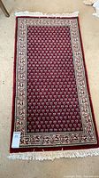 Full view of red patterned runner rug showing design, fringe, and size marker