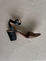 Side view of one sandal showing two-tone straps and block heel