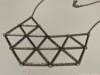 Close-up of textured triangular lattice pendant and chain