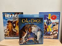 Front view of three cases: Ice Age: Dawn of the Dinosaurs, Cats & Dogs, Rio