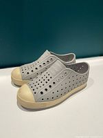 Side view of both shoes showing grey perforated uppers and off-white toe caps
