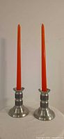 Pair of Haugrud pewter candlestick holders with orange candles for scale