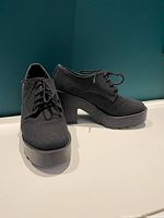 Three-quarter front view of both shoes showing uppers, laces, platform and heel