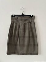 Front view of green plaid high-waisted skirt showing waistband, buttons, pleats and overall condition