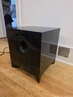Side/front angle of Energy subwoofer showing gloss black cabinet and front port